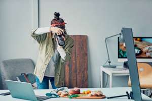 Photographer taking a picture with a camera in a studio with a computer and work desk