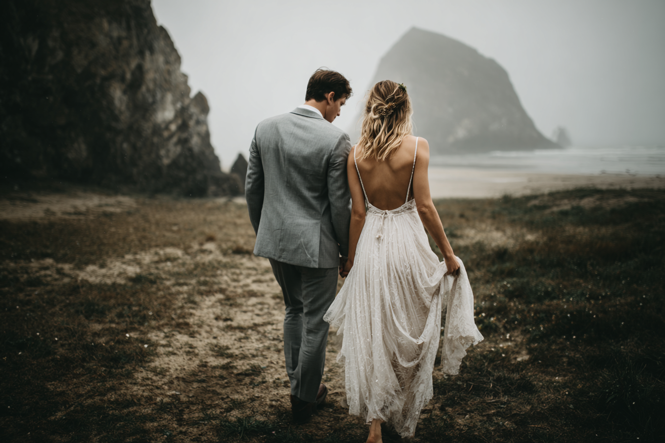 Pareja de novios caminando por la playa durante un reportaje de boda